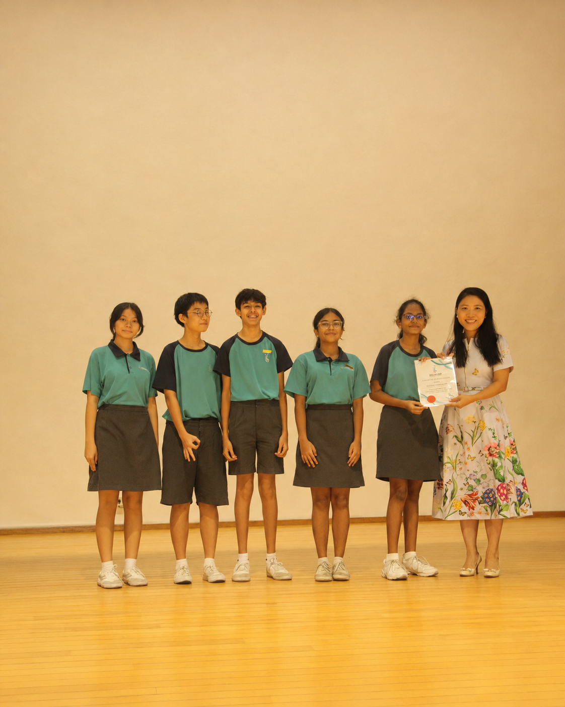 5 students and 1 adult pose for a photo on stage